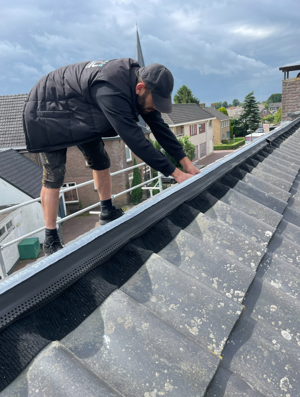 Nokvorst herstel op pannendak in Enschede Dakdekker werkt aan het herstel van de nok van een pannendak op een woning in Enschede.